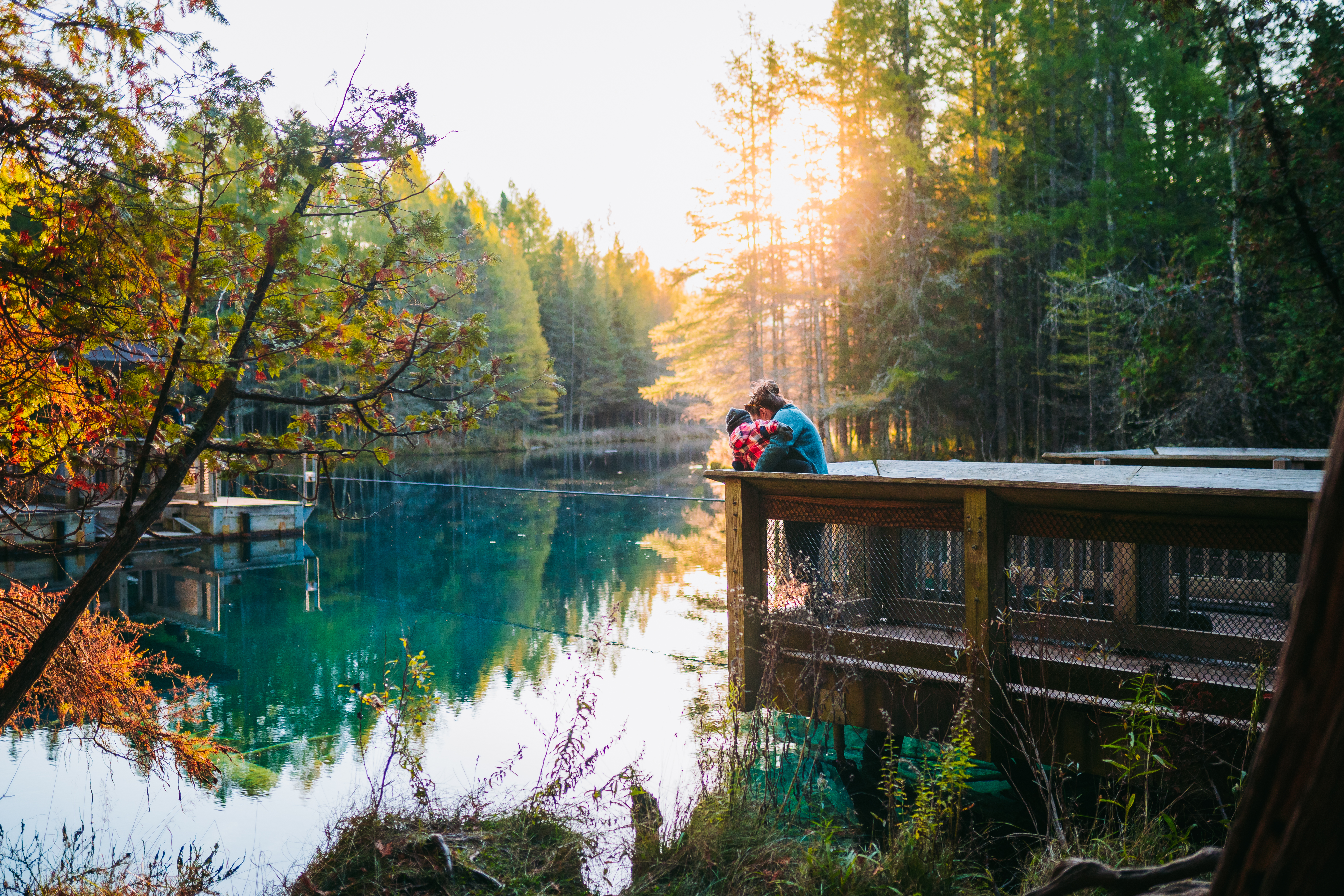 A woman holding a toddler on the dock at Kitch-iti-kipi spring