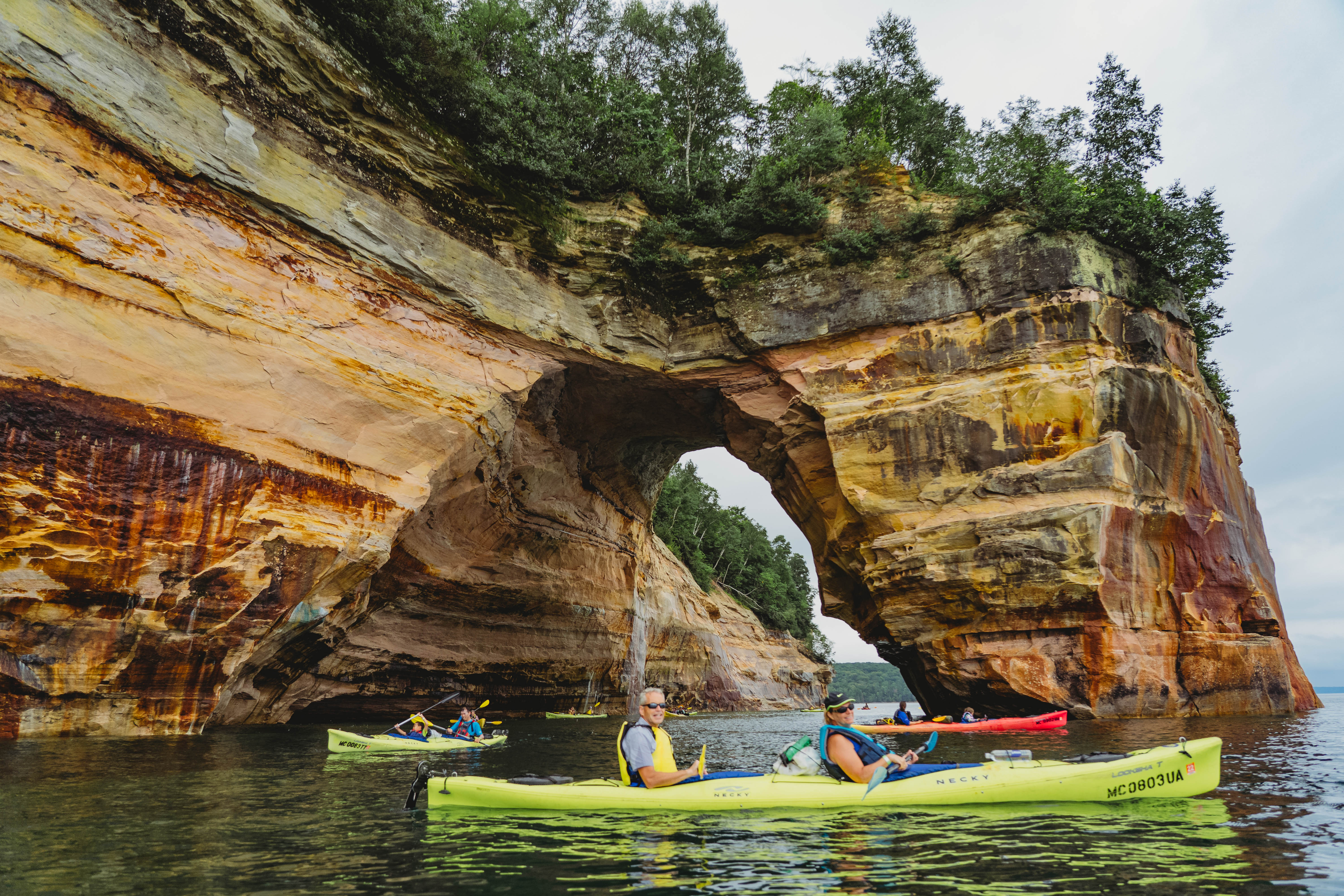 Pictured Rocks National Lakeshore Kayakers paddling by rock arch at pictured rocks national lakeshore.