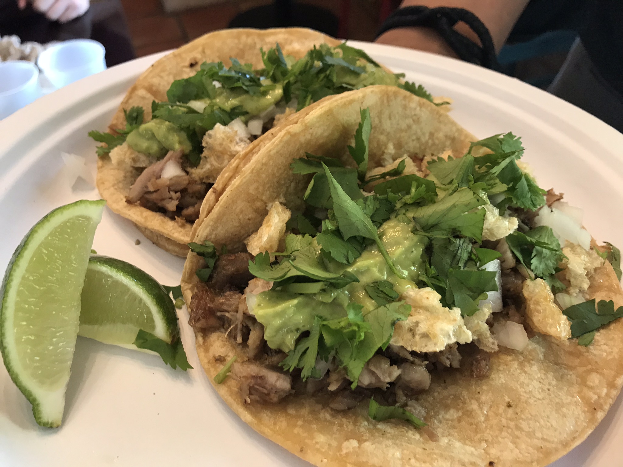 Chela's Restaurant and Taqueria Two tacos with cilantro and onion toppings and a side of lime wedges.