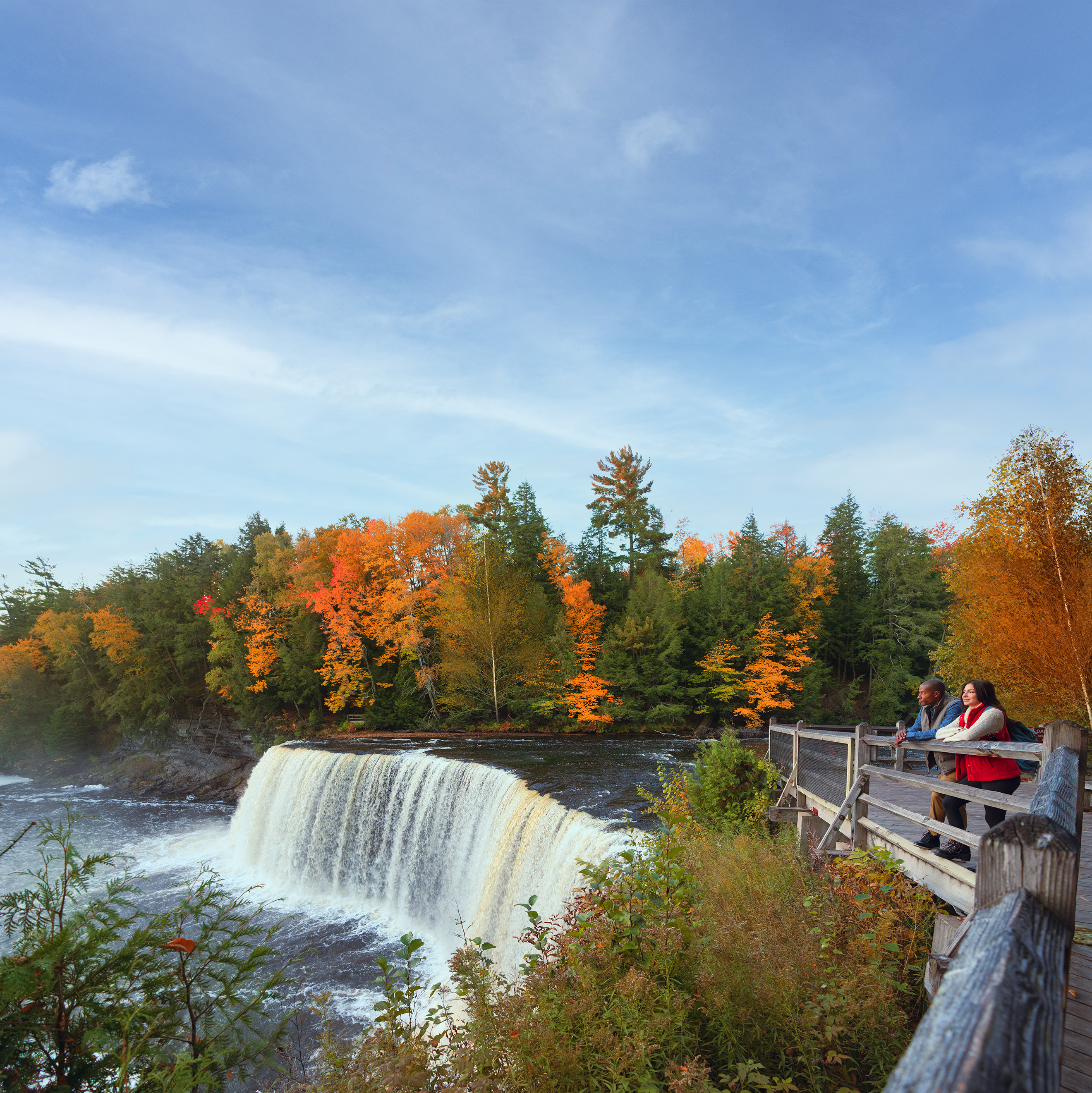 A couple standing on an observation deck beside a waterfall