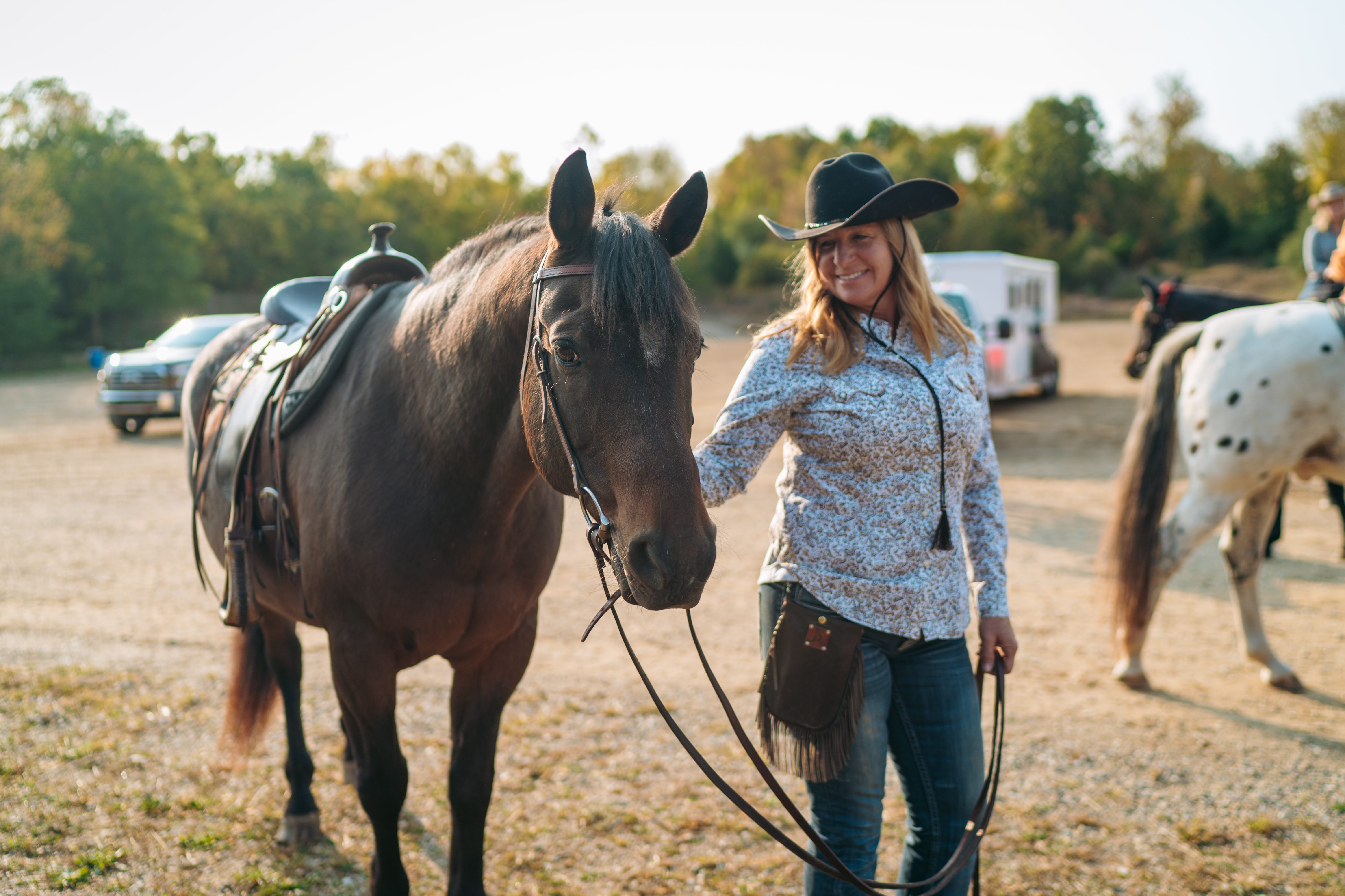 Horseback riding in Michigan A woman leading a horse beside a forset.