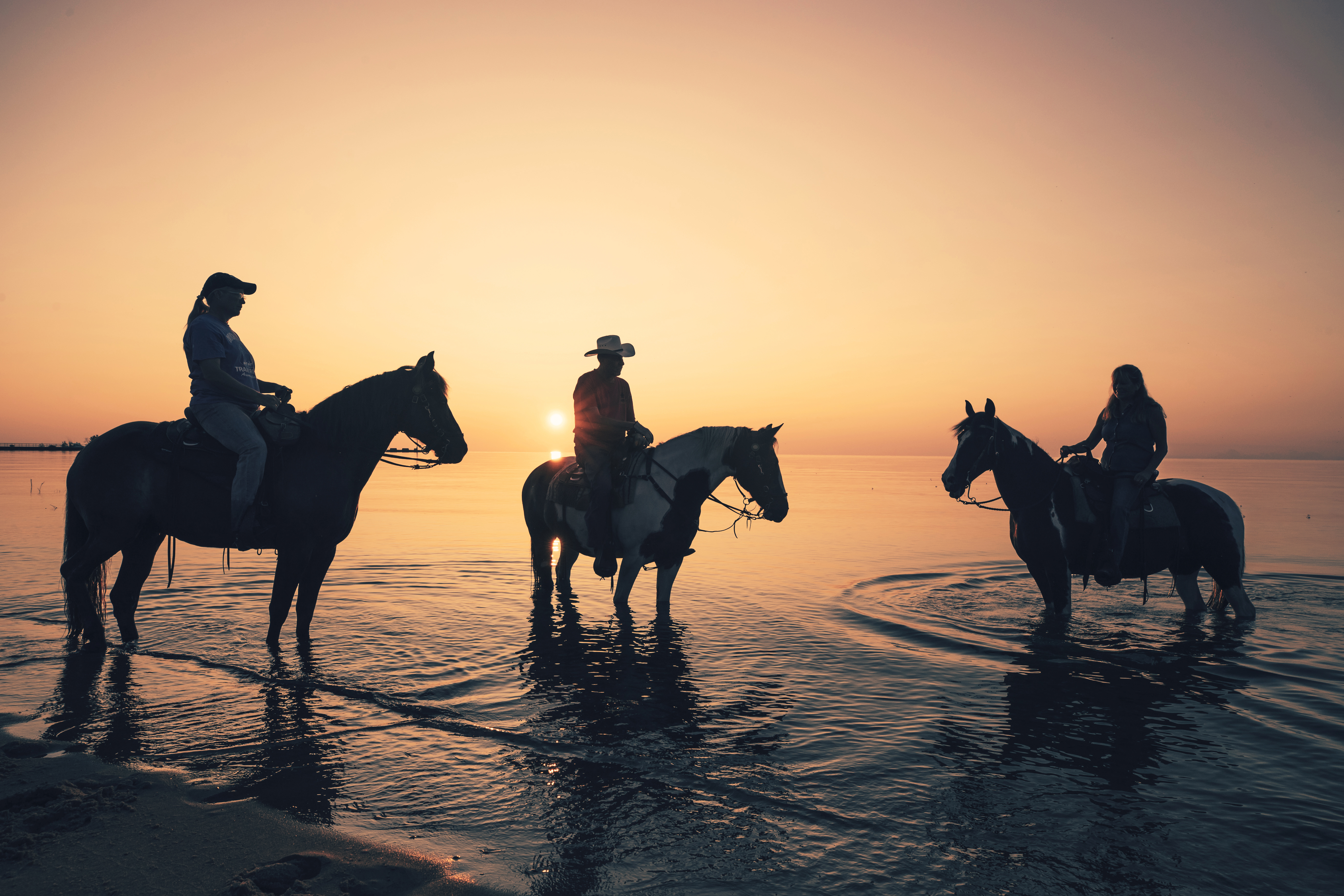 A group of people on horseback standing in Lake Huron