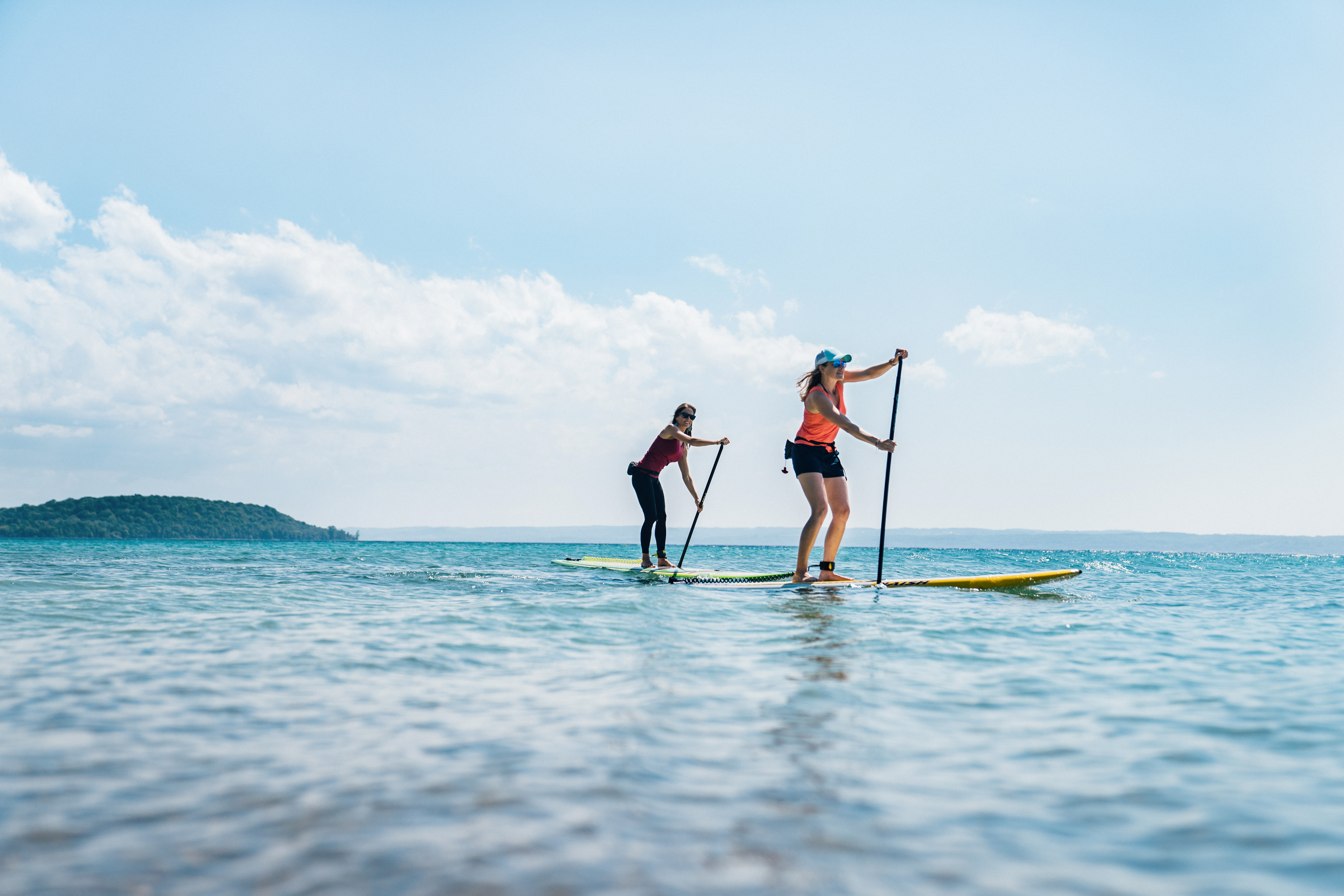 Grand Traverse Bay Two woman stand up paddle boarding on a bay