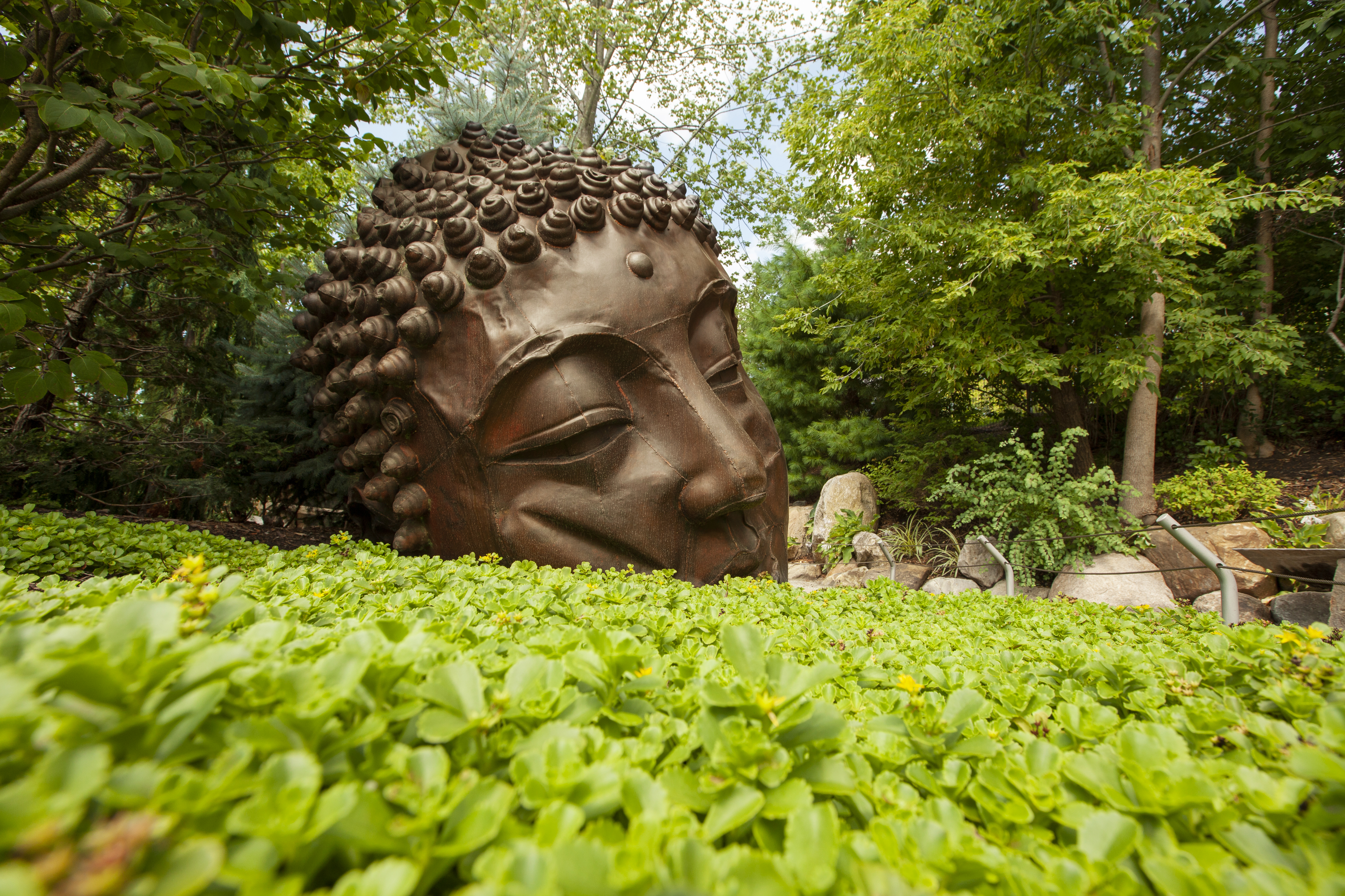 Frederik Meijer Gardens & Sculpture Park by John Noltner A buddha head sculpture sitting in a bed of plants.
