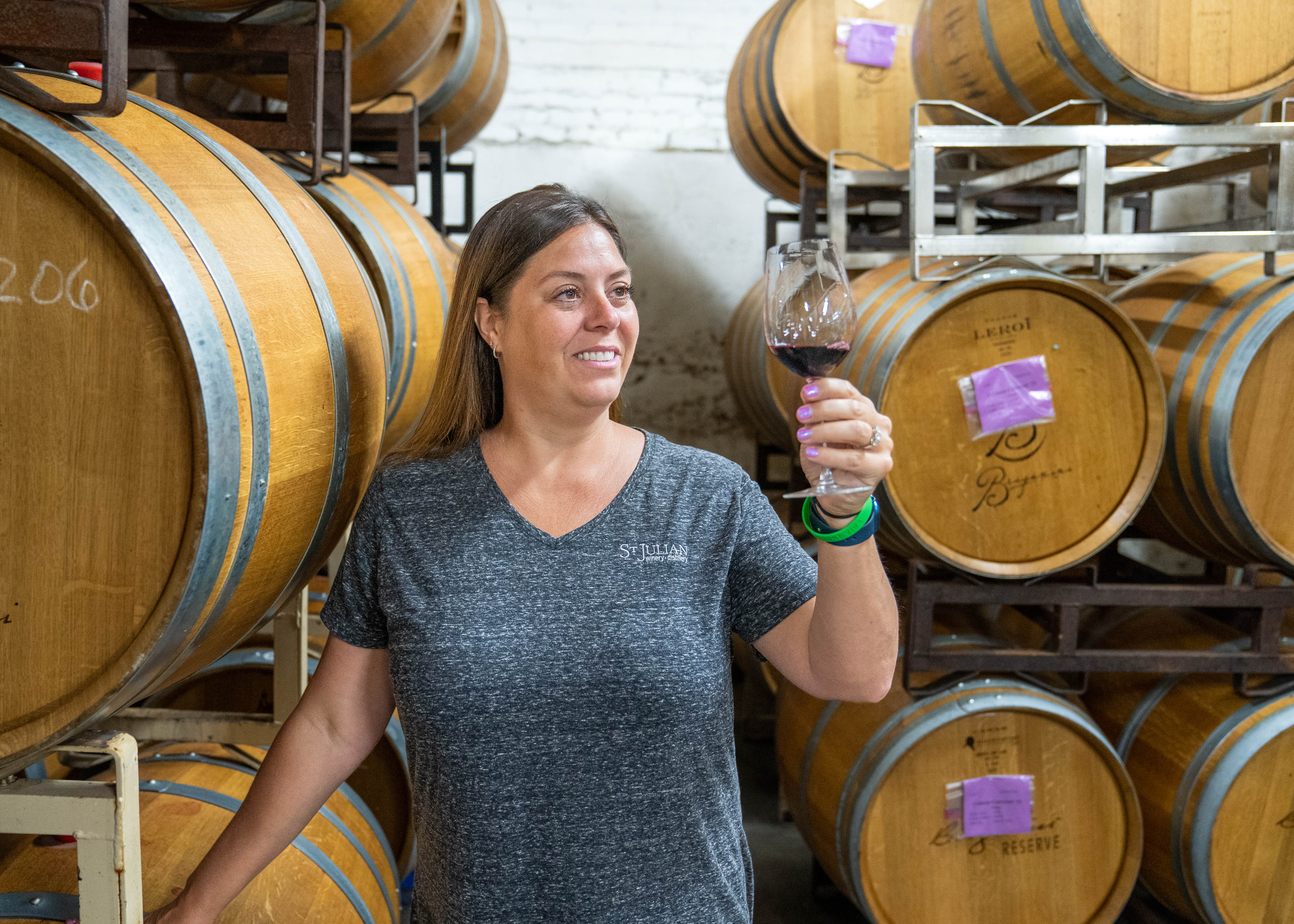 A woman examining a glass of wine poured from a barrel.