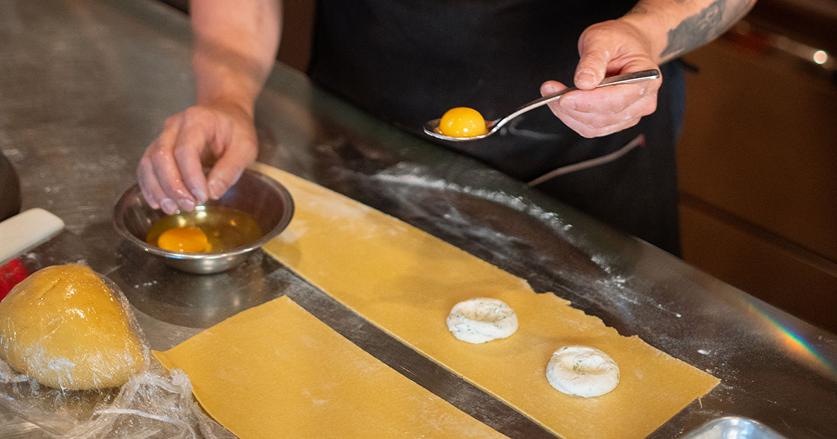 A chef adding filling to handmade ravioli