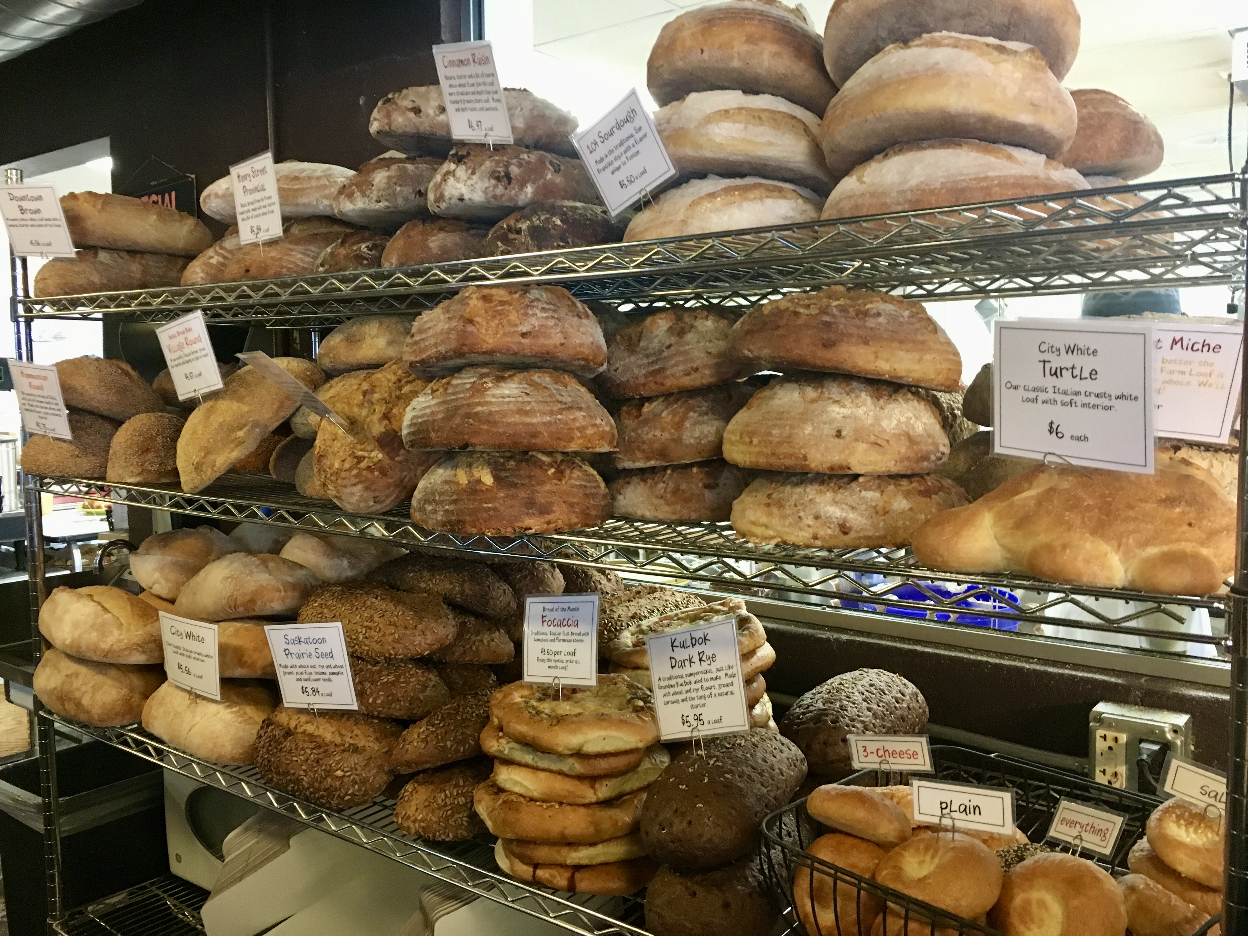 loaves of homemade bread on shelves with papers stating what they are