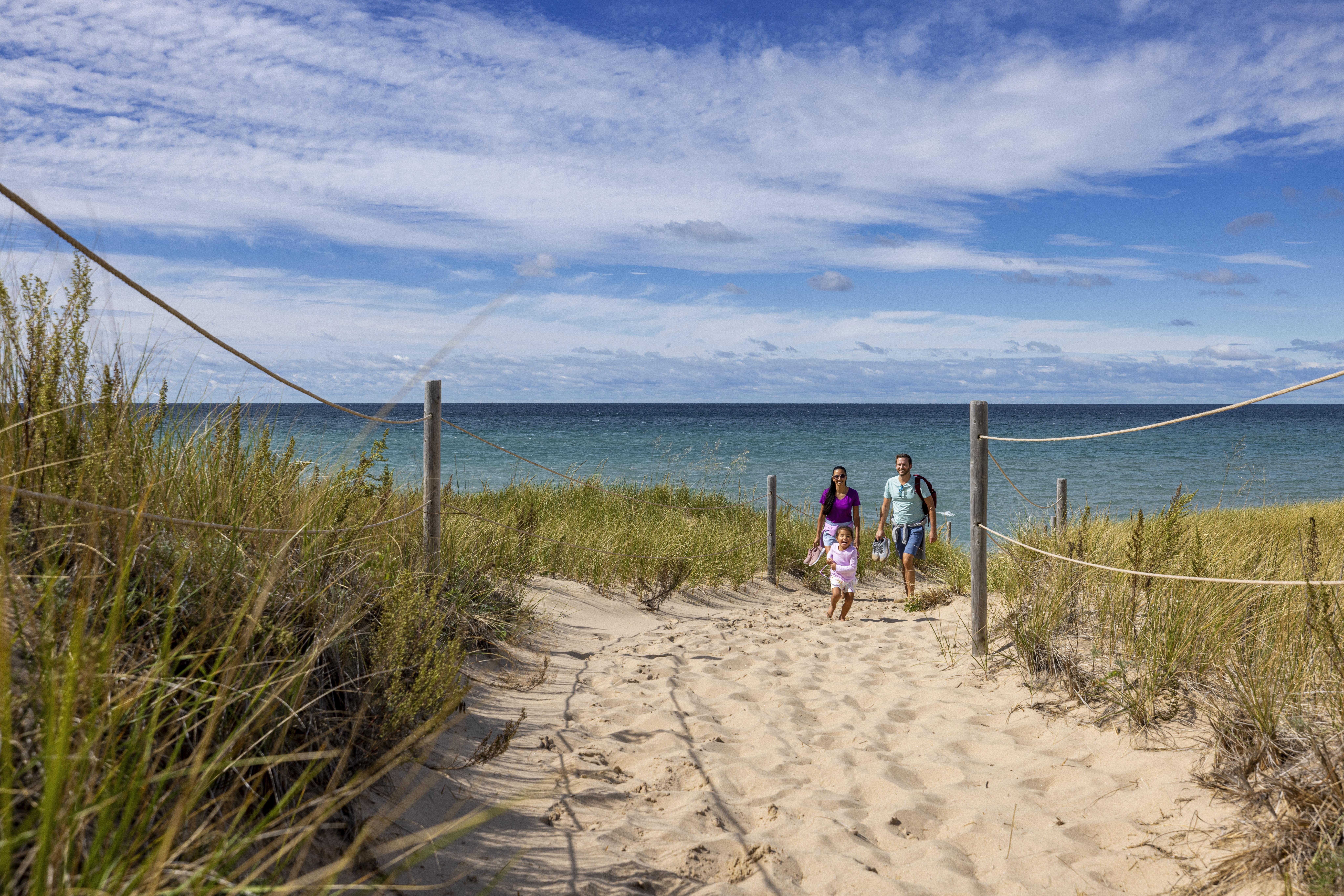 A family with a child walking in the sand along Lake Michigan
