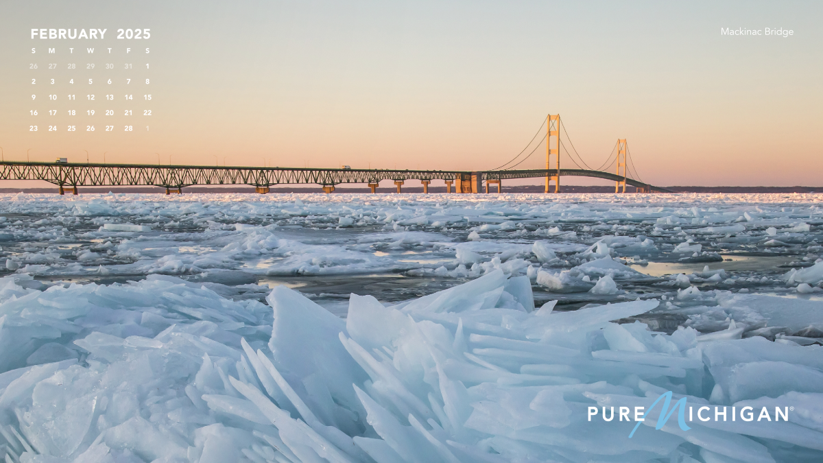 2025 Pure Michigan Calendar | February A photo of ice by the Mackinac bridge with a calendar graphic overlayed.