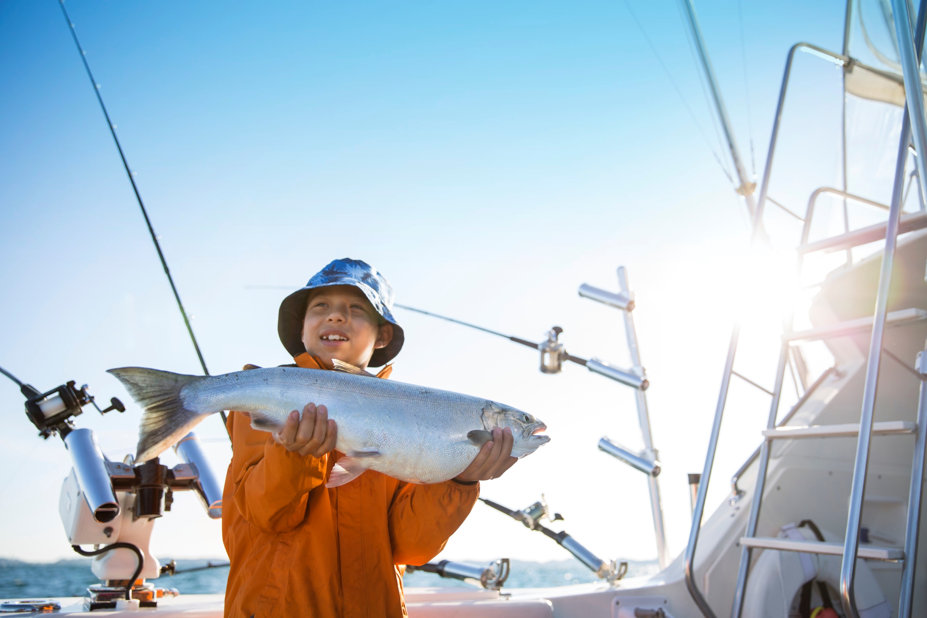 Fishing in Michigan I boy holding a salmon on a boat.