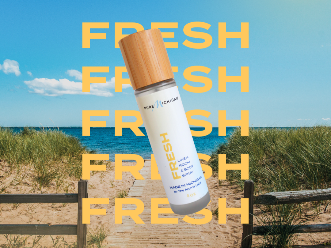 Pure Michigan FRESH Fragrance A graphic design featuring a bottle of the FRESH fragrance on a beach.