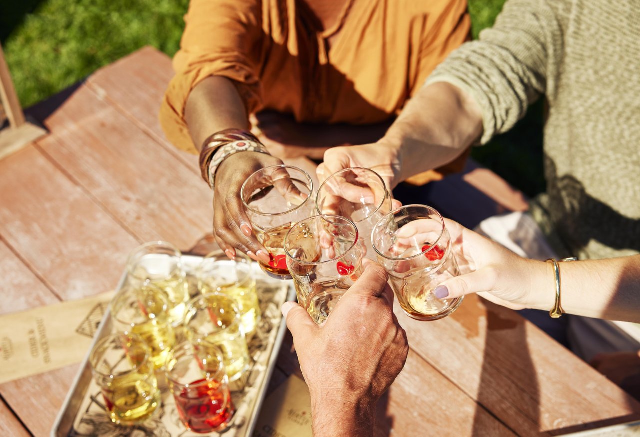 Virtue Cider | Photo Courtesy of Starboard and Port A group of friends toasting with glasses of hard cider at a picnic table.