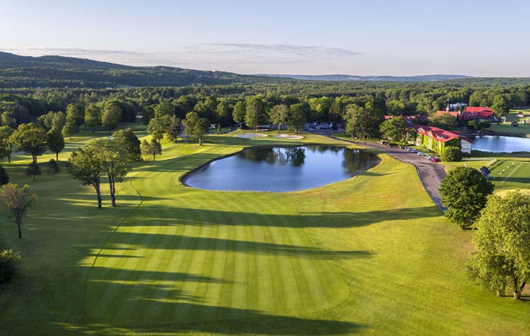 Lush green fairways and a large pond on hole number 18 at The Heather Golf Course at The Highlands in Harbor Springs, Michigan