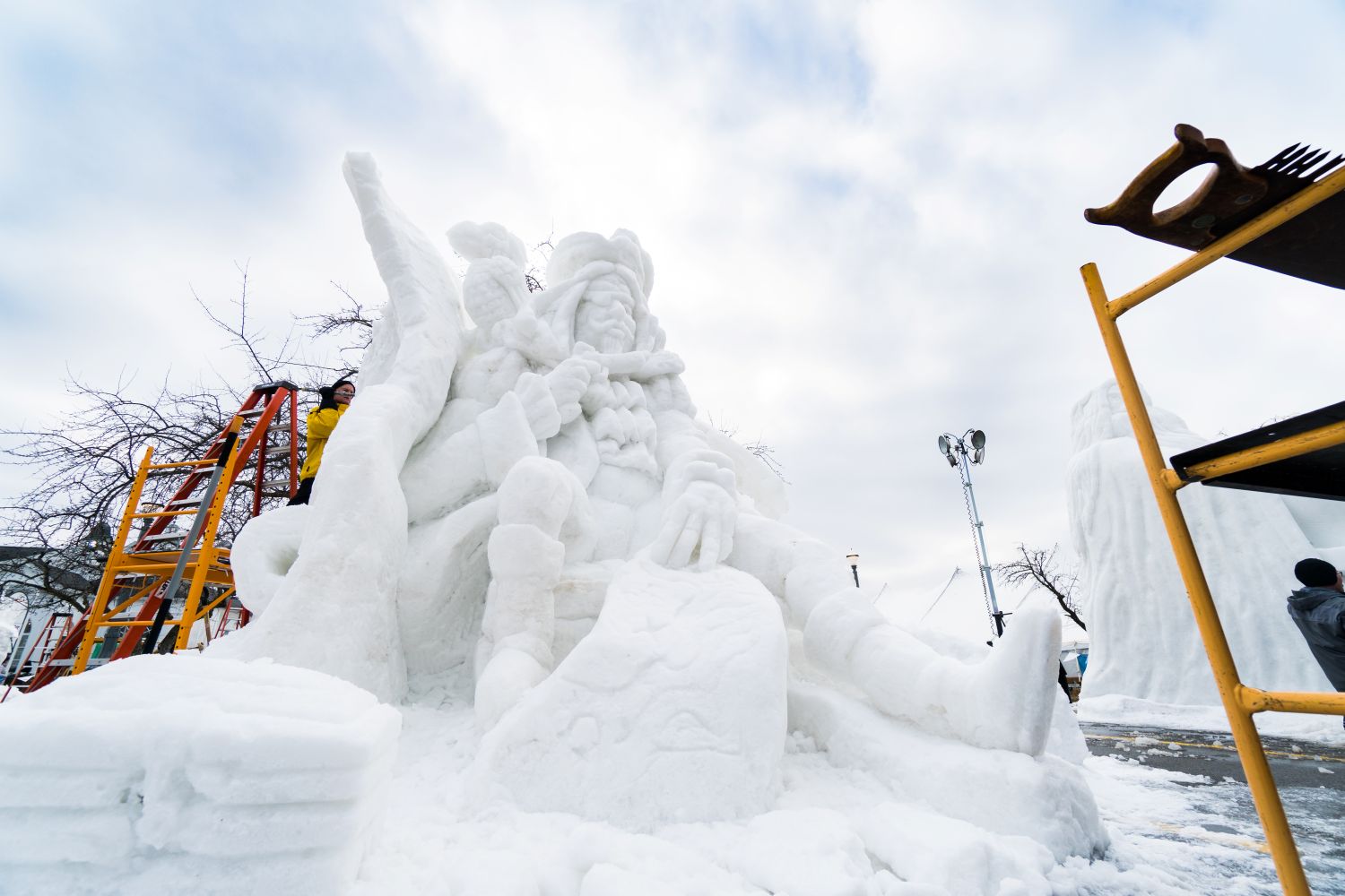 Zehnder's Snowfest A craftsman working on a snow sculpture of a pirate.