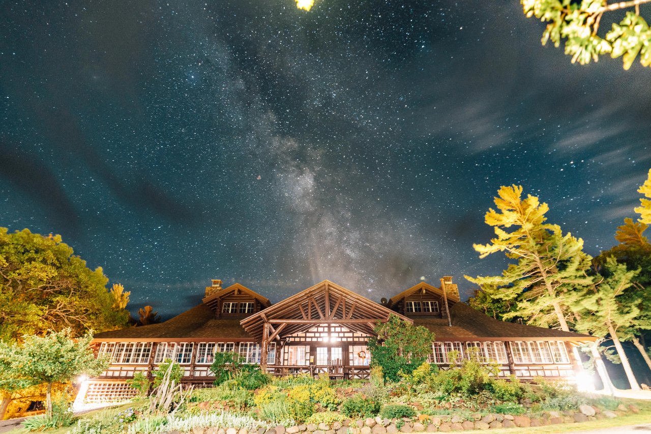 The milky way at night above a log cabin style hotel.