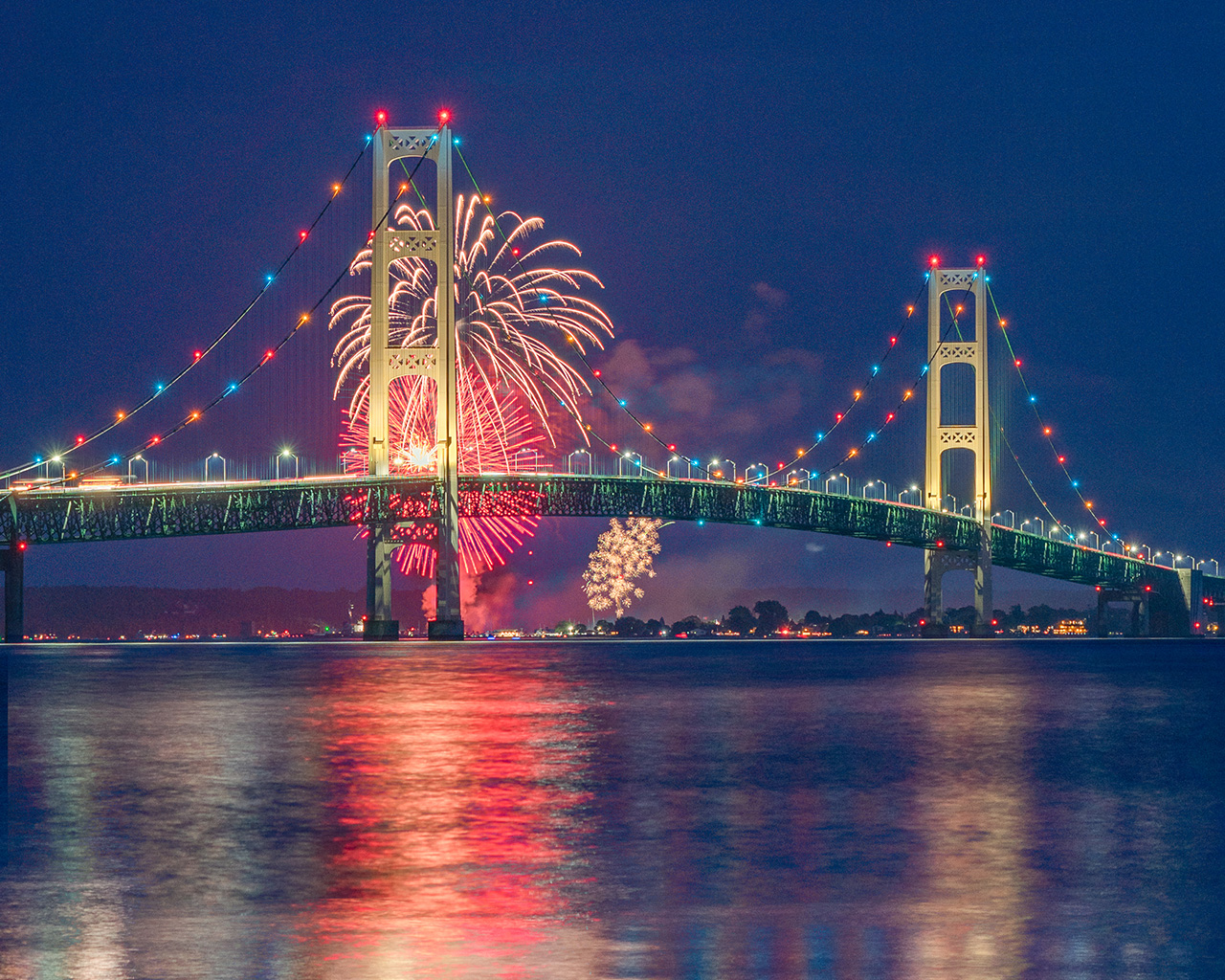 Fireworks in the sky behind the Mackinac Bridge at night. 