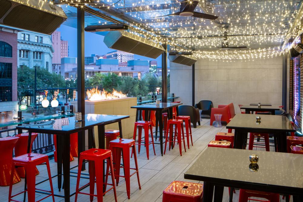 A balcony with tables and a warming fire overlooking downtown Grand Rapids.