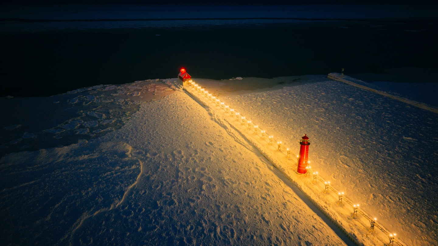 Grand Haven Lighthouse illuminated at night and surrounded by ice. 