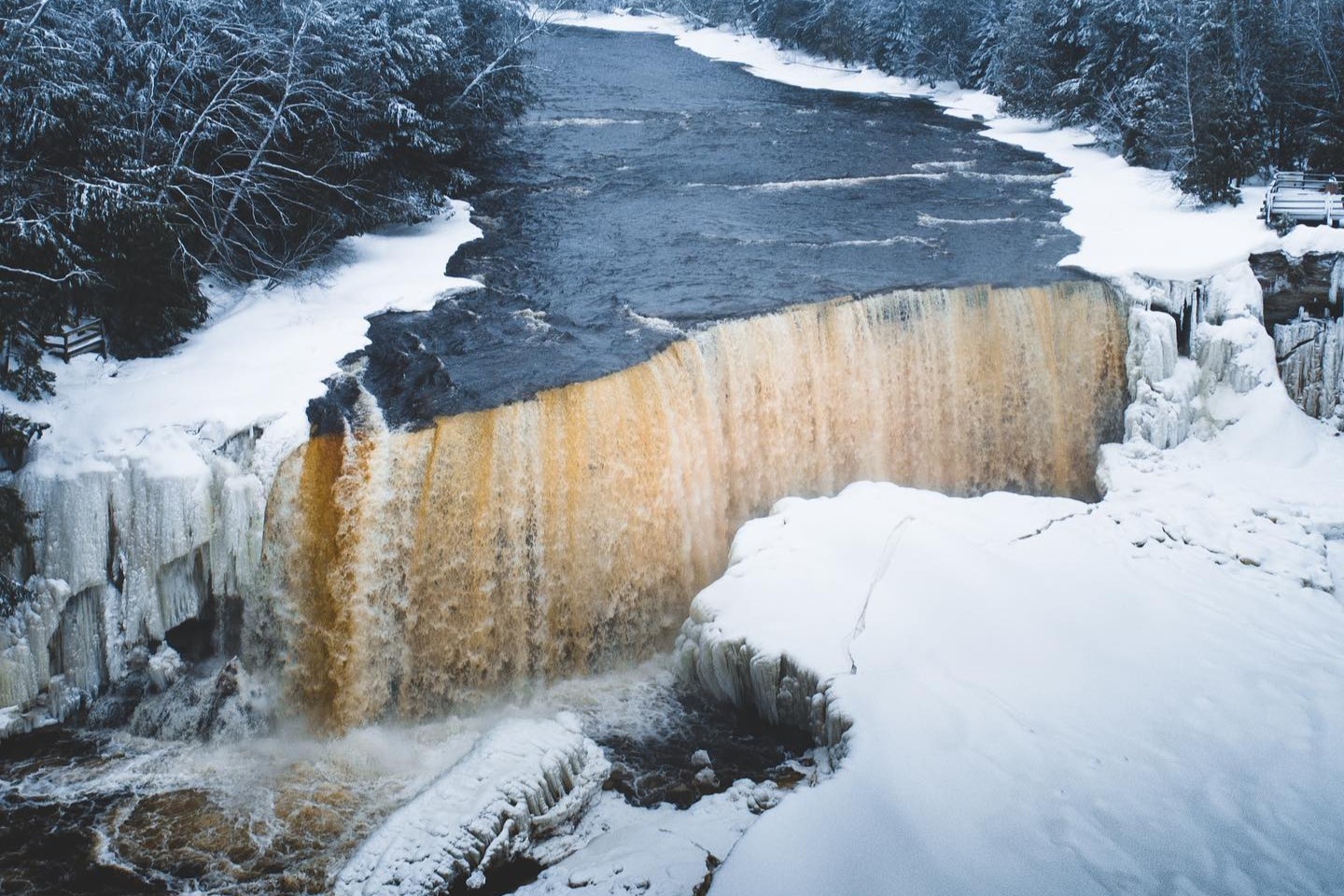Waterfall surrounded by a snowy forest and ice. 