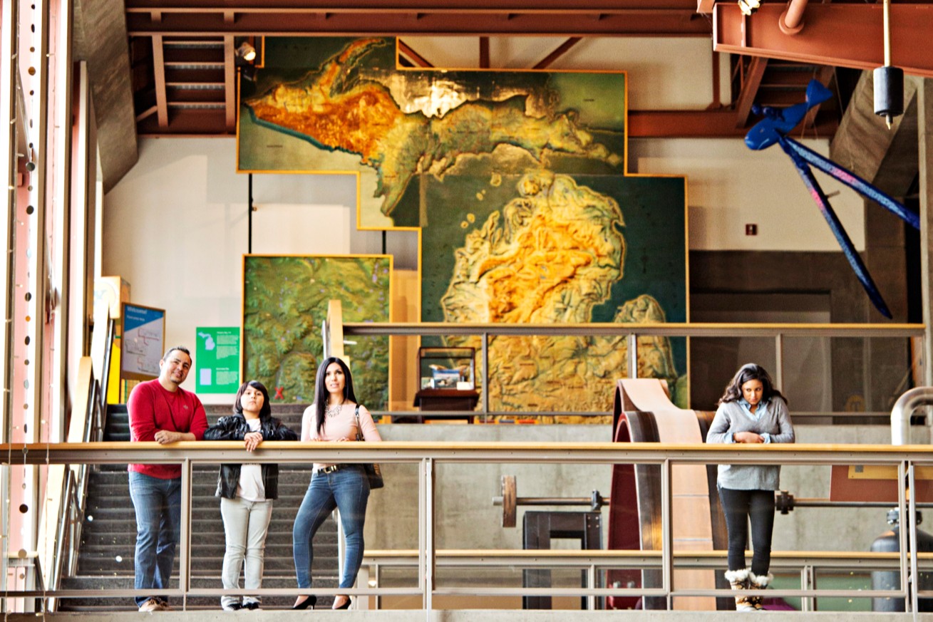 Museum-goers near a ceiling-height topographical map of Michigan. 