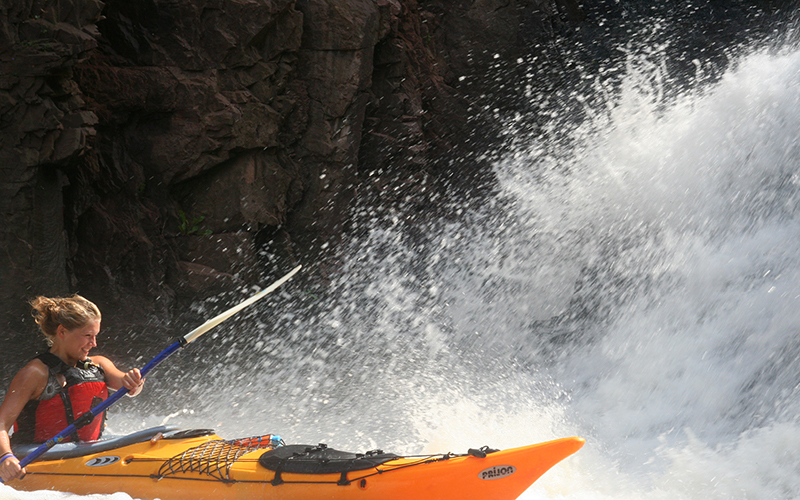 girl in a yellow kayak paddling the rapids