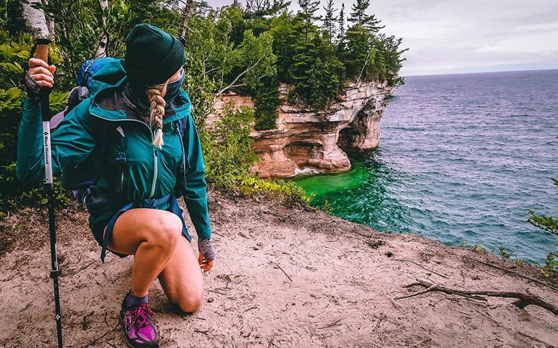 person hiking the lake superior shoreline water is aqua blue