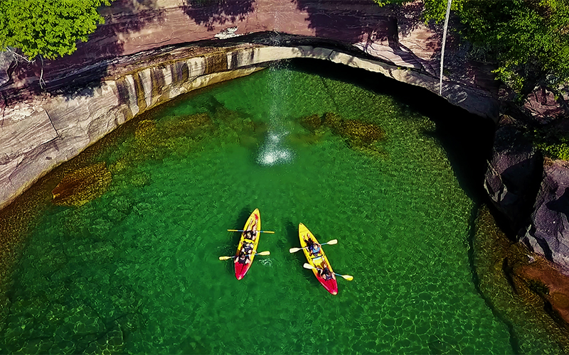 aerial view looking down on kayakers by the cliffs - water is gree