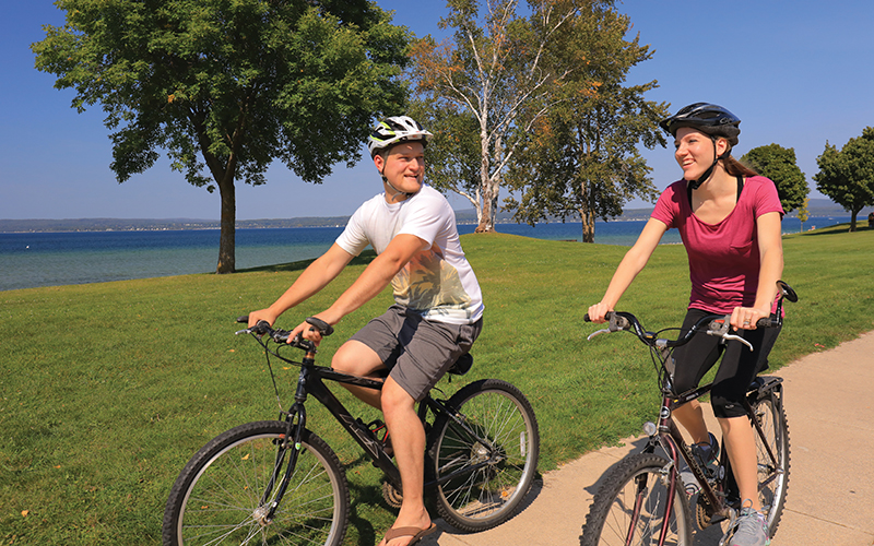 two ladies on their bikes on a paved bike path - sky is blue