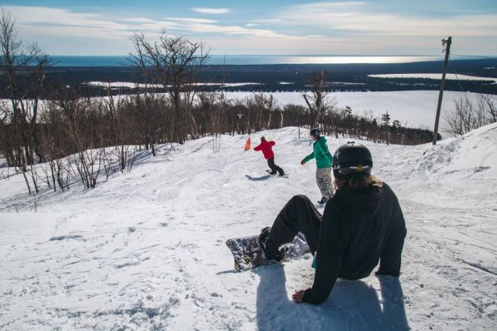 Snowboarder sitting on snow at Mt. Bohemia