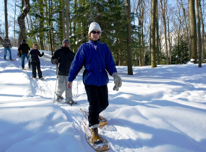 Group snowshoeing through snowy forest.