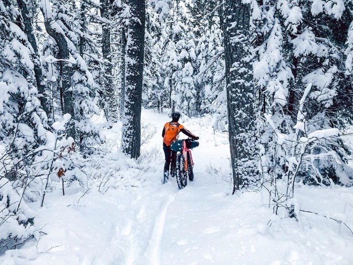 Woman walking fat tire bike through snow