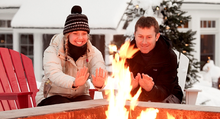Couple sitting at campfire during winter.