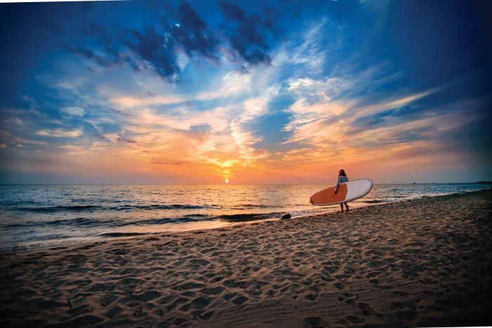 Paddle boarder walking on Grand Haven beach.