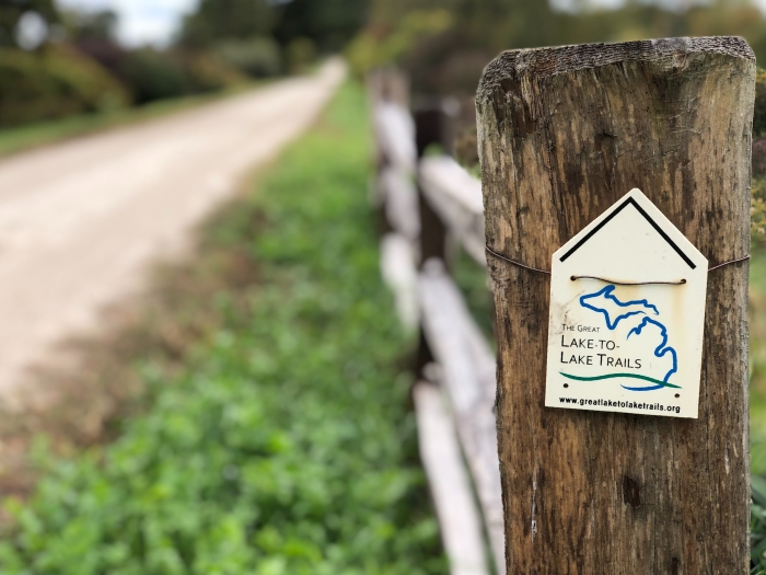 Trail sign reading "The Great Lake-to-Lake Trails" beside a trail.