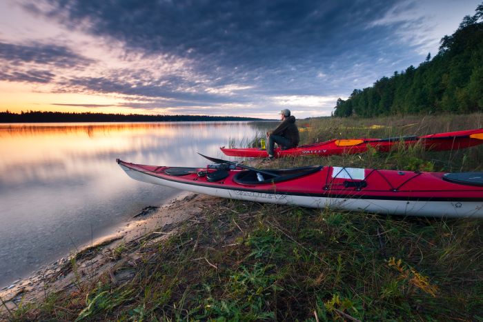 Kayaker sitting on river bank at sunset