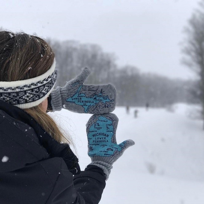 A girl in the snow with mittens on.
