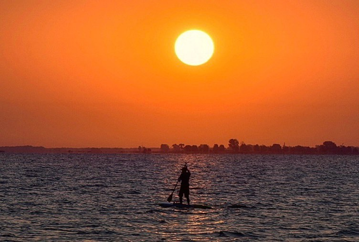 Paddleboarder on the water at sunset.