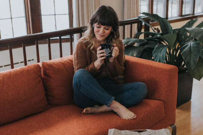 Woman sitting on a cough with a Michigan-themed coffee mug.