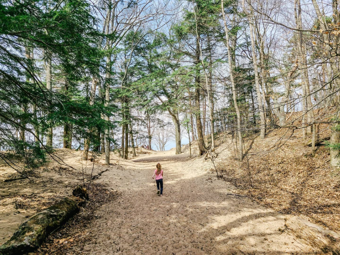 A girl walking on a sandy trail at Saugatuck Dunes State Park.
