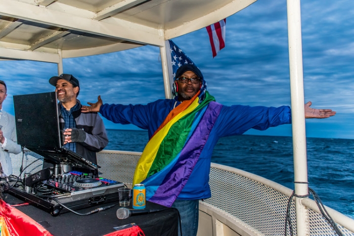 DJ wearing a pride flag on a boat on Mackinac Island.