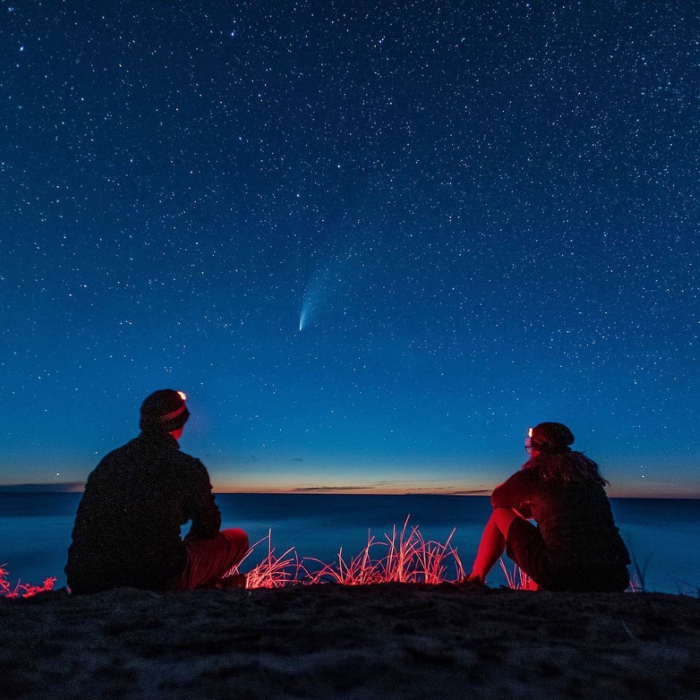 Two stargazers look out at a shooting star over Lake Superior.