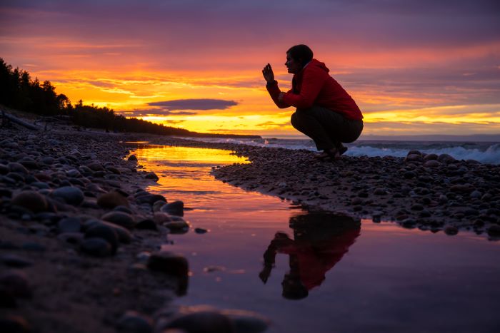 Woman searching for Yooperlites along Lake Superior at sunset.