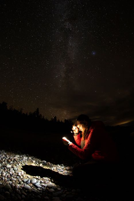 Woman searching for Yooperlites under the Milky Way at night