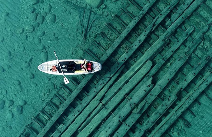 Diver resting on paddle board above shipwreck
