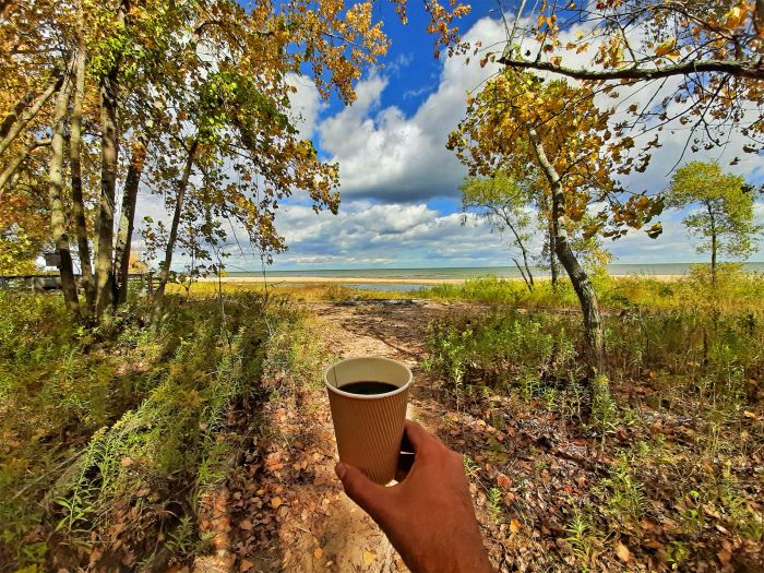 Aaron Cruz holding coffee on shoreline at Bay City State Park