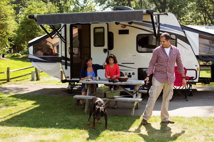 A family sits around a picnic table on their campsite