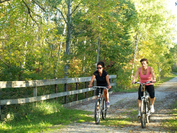 Two women biking on a trail. 