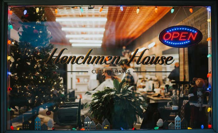 Henchmen House storefront window decorated with lights and a Christmas Tree. 