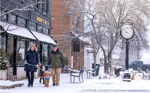 Couple walking with dog in downtown Saugatuck during winter.