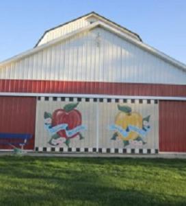 exterior of fruit market barn, doors have paintings of apples on them, sky is bright
